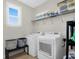 Bright laundry room featuring white washer and dryer, overhead storage, and natural light from a window at 2961 Yachtsman Dr, Mount Pleasant, SC 29466