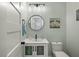 Modern half bath features a round mirror, vanity and decorative artwork at 3308 Island Estates Dr, Johns Island, SC 29455