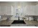 Granite countertops accent a modern kitchen with a black sink and white cabinets at 3308 Island Estates Dr, Johns Island, SC 29455