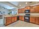 Well-lit kitchen with light countertops, wood cabinets, and black appliances overlooking an open living area at 343 Iveson Rd, Summerville, SC 29486