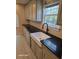 Close-up of kitchen sink featuring a white farmhouse sink, black countertops, and neutral cabinets at 399 Stefan Dr, Charleston, SC 29412