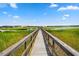 Long wooden dock leading to a peaceful waterfront with marsh views under a bright blue sky at 430 Fish Tale Rd, Charleston, SC 29492