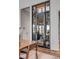 View of wine cellar behind a black-trimmed glass door, adjacent to a wooden dining table at 430 Fish Tale Rd, Charleston, SC 29492