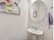 Charming powder room with a decorative mirror, modern pedestal sink, and soft neutral wall color at 509 Purple Finch Rd, Summerville, SC 29486