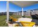 Covered backyard patio with yellow chairs, lush green lawn, and a view of the fenced yard and lake beyond at 538 Spanish Wells Rd, Summerville, SC 29486