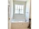 Bathroom featuring a soaking tub under a bright window, set in a white tiled surround at 572 Tidewater Chase Ln, Summerville, SC 29486