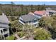 Aerial shot showcases a light-blue, two-story home with wrap-around porches, with mature palm trees and landscaping at 740 Stucco Ln, Mount Pleasant, SC 29464