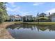 Scenic view of the backs of several homes reflected on a tranquil pond surrounded by lush greenery on a sunny day at 740 Stucco Ln, Mount Pleasant, SC 29464