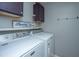 Bright laundry room with modern washer and dryer, overhead cabinets, and 