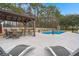 Relaxing poolside area with sun loungers, dining set under a pergola, and beautifully landscaped surroundings at 117 Hartin Blvd, Summerville, SC 29486