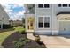 Close up of a charming two-story home featuring a yellow door, complemented by manicured landscaping at 1457 Red Tide Rd, Mount Pleasant, SC 29466