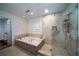 Luxurious bathroom featuring a corner tub, a tiled shower with glass door, and neutral tile at 2014 Ion Ave, Sullivans Island, SC 29482