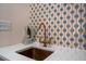 Close-up of a sink featuring beautiful mosaic tile backsplash and unique brass faucet at 2014 Ion Ave, Sullivans Island, SC 29482