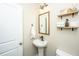 Stylish half-bathroom with pedestal sink, decorative mirror, open shelves, and modern light fixture at 204 Torslanda Ln, Summerville, SC 29486