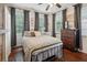 Well-lit bedroom with hardwood floors featuring a bed, dresser, and multiple windows with curtains at 21 America St, Charleston, SC 29403