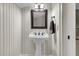 Charming bathroom with pedestal sink, wood paneling, decorative mirror, and elegant light fixtures at 2292 Beckenham Dr, Mount Pleasant, SC 29466