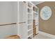 Spacious walk-in closet with custom shelves, wooden rods, and a round window for ample natural light at 2292 Beckenham Dr, Mount Pleasant, SC 29466