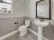 A stylish powder room features a pedestal sink, a decorative mirror, and patterned wallpaper at 253 Palmetto Walk Dr, Summerville, SC 29486