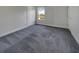 Bright bedroom featuring plush gray carpet, neutral walls, and a sunlit window overlooking the backyard at 253 Palmetto Walk Dr, Summerville, SC 29486