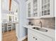 Butler's pantry with marble countertop, stylish sink, gray backsplash and cabinetry with glass doors at 2912 Yachtsman Dr, Mount Pleasant, SC 29466