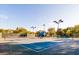 Well-maintained tennis court with a blue surface, surrounded by greenery and professional lighting at 2912 Yachtsman Dr, Mount Pleasant, SC 29466