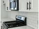 Close up of a stainless steel microwave and range with white cabinets and white subway tile backsplash at 310 Woodland Shores Rd, Charleston, SC 29412
