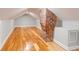 Renovated attic featuring hardwood floors, white walls, and a charming brick chimney at 4625 Durant Ave, North Charleston, SC 29405