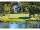 Tranquil pond view through trees, showcasing a well-maintained golf course and the charming home in the background at 5208 Holly Forest, Hollywood, SC 29449
