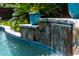 Close-up of pool waterfall feature with stone accents and lush landscaping at 5556 Indigo Fields Blvd, North Charleston, SC 29418
