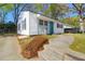 Charming home featuring light siding, black shutters, a blue front door, and a well-maintained yard with mature trees at 5801 Chaucer Dr, Hanahan, SC 29410