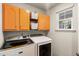 Well-lit laundry room with stainless steel washer and dryer, bright orange cabinets, and natural light at 6005 Coral Berry Rd, Hanahan, SC 29410