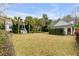 Large backyard featuring a lush lawn, mature palm trees, and additional structures on the property at 7 Guerard Rd, Charleston, SC 29407