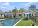 Stunning backyard featuring a modern pool, manicured lawn, outdoor seating and palm trees, perfect for relaxation and entertainment at 7858 Gull Bay Dr, Awendaw, SC 29429
