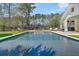 Backyard featuring a pool, spa, outdoor kitchen, and lush greenery, offering a private and luxurious oasis for relaxation and entertaining at 7858 Gull Bay Dr, Awendaw, SC 29429