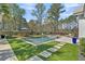 Beautiful backyard with swimming pool, spa and artificial turf, surrounded by lush greenery and mature trees for privacy at 7858 Gull Bay Dr, Awendaw, SC 29429
