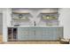 Stylish basement bar area with light gray cabinets, shelving, wine cooler, and light wood floors at 8638 Scottish Troon Ct, North Charleston, SC 29420