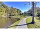 A serene view featuring a winding pathway beside a tranquil pond and lush greenery at 8638 Scottish Troon Ct, North Charleston, SC 29420