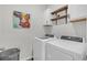 Bright laundry room features white washer and dryer, floating shelves, and stylish laundry basket at 9700 Flooded Field Drive Dr, Ladson, SC 29456