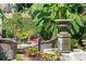 Inviting brick patio showcases a tranquil water fountain, red flowers, and comfortable wicker chairs and tables at 10 Water St, Charleston, SC 29401