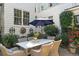 Private backyard patio featuring a dining table, wicker chairs, lush greenery, and charming architectural details at 10 Water St, Charleston, SC 29401