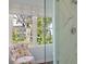 Bathroom featuring a marble walk-in shower, glass door and floral chair by large window at 10 Water St, Charleston, SC 29401