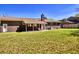 Spacious backyard with a brick house featuring a chimney and a covered patio under a clear blue sky at 1198 Oakcrest Dr, Charleston, SC 29412