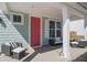 Inviting front porch with a cozy seating area, a bright red door, and stylish decor at 1427 Homecoming Blvd, Ravenel, SC 29470
