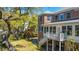 Brick home exterior with screened porch, back staircase, and lush landscaping including mature trees at 1521 Hurtes Island Dr, Charleston, SC 29407