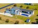 Bird's eye view of a white farmhouse with an in-ground pool, an outdoor living space, a three car garage and a long driveway at 161 Ryefield Ln, Ridgeville, SC 29472