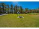 Expansive backyard with a fire pit, pool fence, and storage buildings, nestled among mature trees at 161 Ryefield Ln, Ridgeville, SC 29472