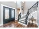 Grand foyer with a striking staircase, elegant lighting, and decorative front doors at 161 Ryefield Ln, Ridgeville, SC 29472