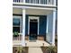 Inviting blue home featuring a black front door, stone accents, white columns, and manicured landscaping at 1659 Seabago Dr, Charleston, SC 29414