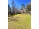 Expansive backyard showcasing a large grassy area surrounded by mature trees under a sunny blue sky at 1848 Merrick Dr, Round O, SC 29474