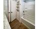 Well-lit bathroom with tub-shower combo, shelving, and wood-look vinyl floors at 1848 Merrick Dr, Round O, SC 29474